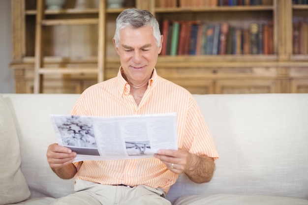 年配の男性がリビングルームで新聞を読む