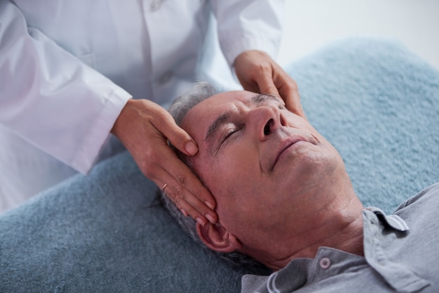 Senior man receiving head massage from physiotherapist