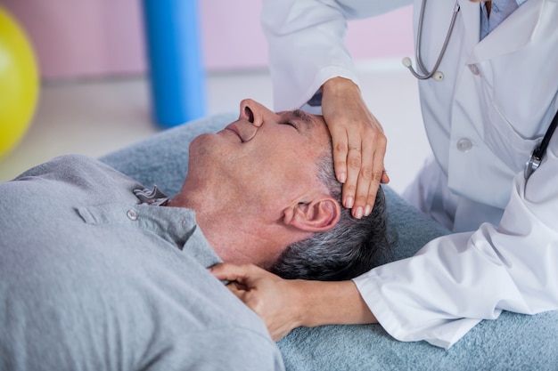 Senior man receiving neck massage from physiotherapist