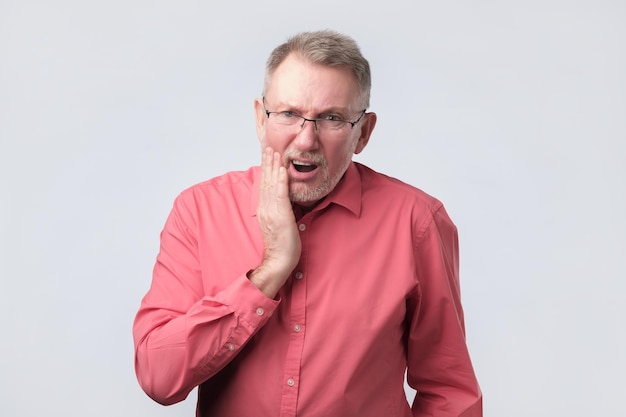 Senior man in red shirt suffering from tooth pain