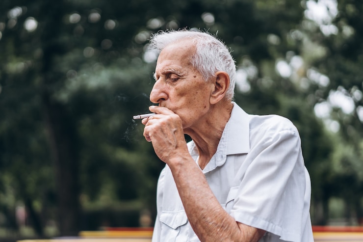 Foto senior man roken sigaret buiten in het stadspark