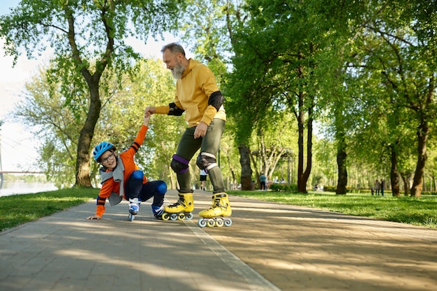 Senior man rolschaatsen met kleine jongen in stadspark