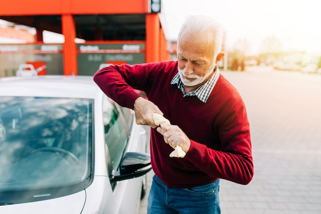 Senior man schoonmaak auto met doek, auto detaillering (of valeting) concept.