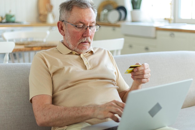 Senior man shopping online using laptop paying with credit card old grandfather buying on internet