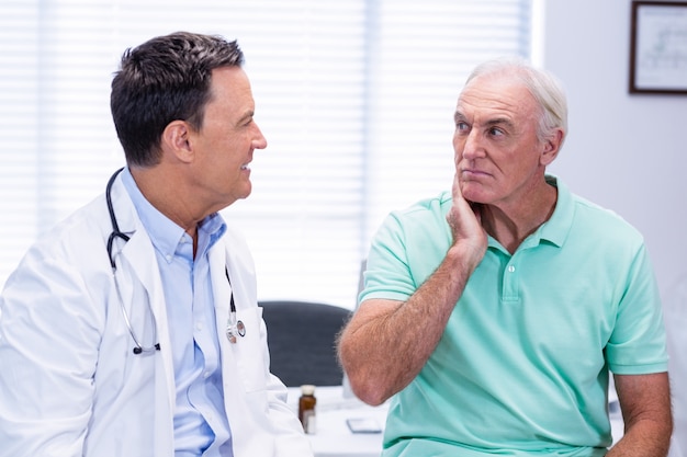 Senior man showing neck pain to doctor