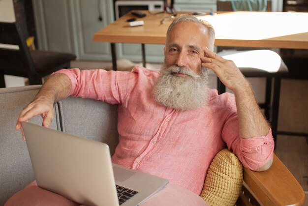 Senior man sitting on a sofa in front of a laptop computer