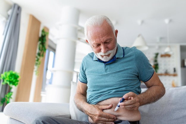 Senior man sitting on sofa and giving himself an insulin injection for his diabetes