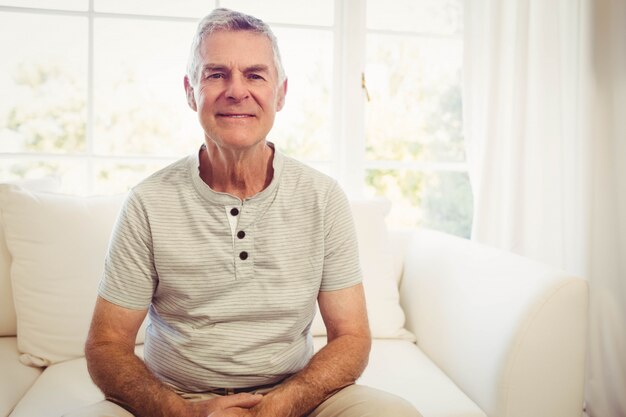 Senior man sitting on sofa smiling at the camera