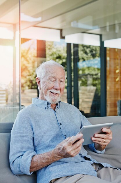Старший мужчина сидит на террасе и читает электронную книгу