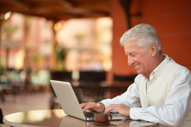 Senior man sitting with laptop in hotel