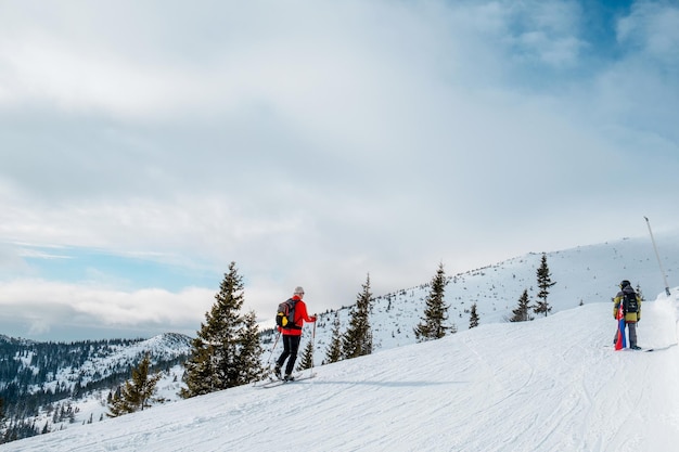 Лыжный тур пожилого человека идет вверх, глядя на пейзаж
