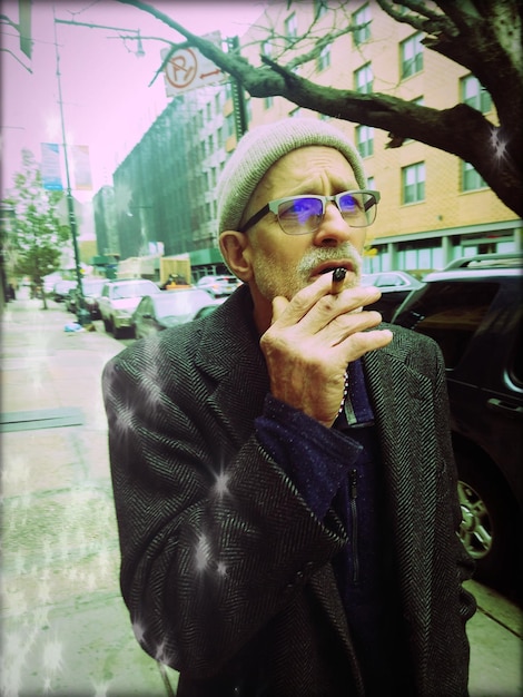 시내 의 보행자 길 에 서 있는 노인 이 담배 를 피우고 있다