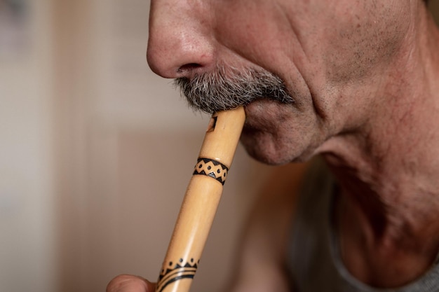 Senior man speelt de fluit gezichtsloze onprofessionele man van oudere blanke recorder mensen met een snor met mond en lippen spelen op pijp amateurmuziek close-up thuis hobby's en vrije tijd