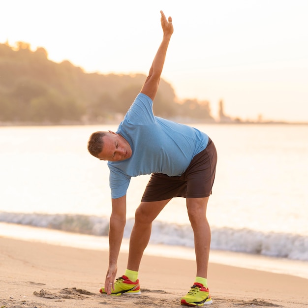 Photo senior man stretching on the beach