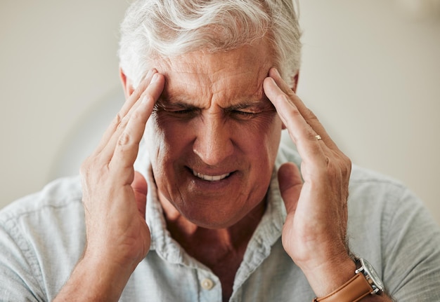 Senior man suffering with headache pain from stress and painful head migraine Elderly people at risk for mental health problems like anxiety and depression or loneliness from old age in retirement