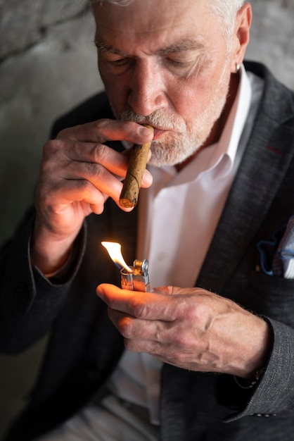 Photo senior man in suit lighting a cigar