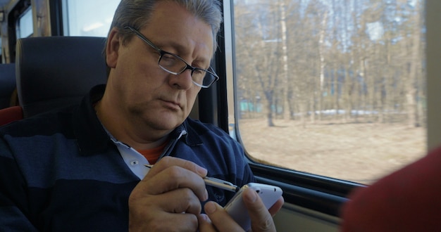 Senior man surfing the internet on cellphone in train