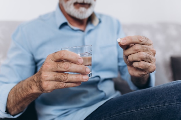 Senior man taking medicine at home.