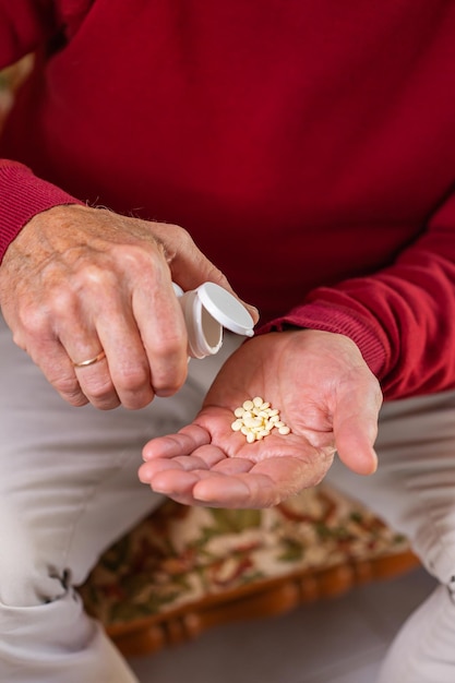 Senior man taking medicine pills supplement closeup of hands