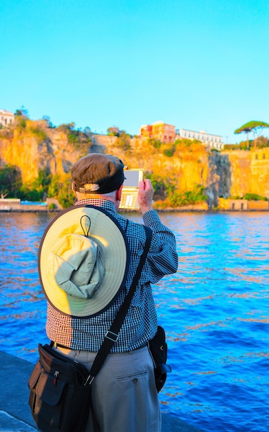 Foto uomo anziano che scatta foto sul telefono cellulare a marina grande a sorrento, mar tirreno, costiera amalfitana, italia. estate