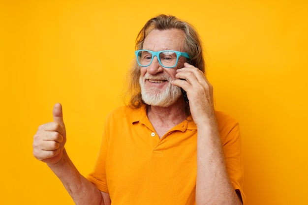 Senior man talking on phone against yellow background