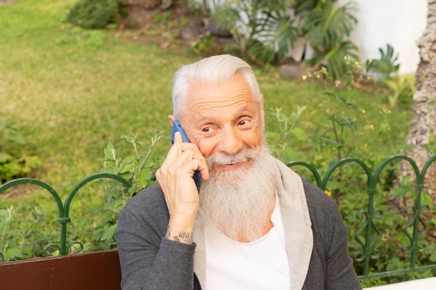 senior man talking on a phone on sea beach distant online work and bussiness concept senior people lifestyle