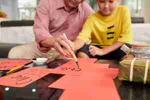 Photo senior man teaching granson to create greeting cards for chinese new year