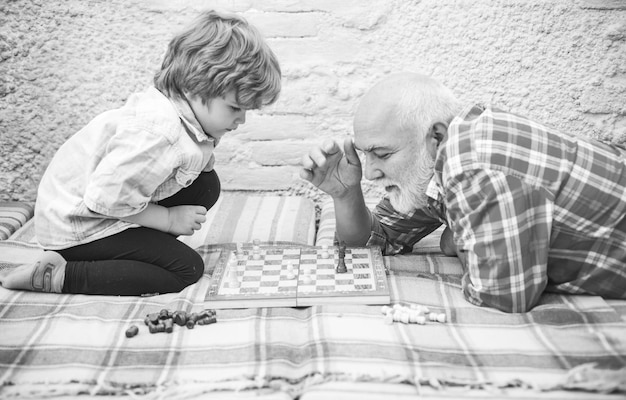 Photo senior man teaching his grandson to play chess handsome grandpa and grandson are playing chess while