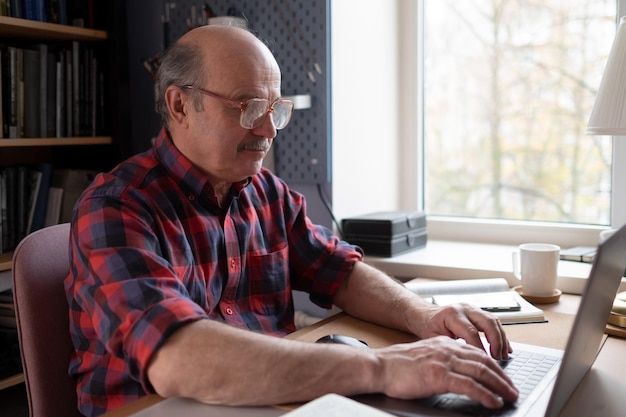 Senior man thuis voor laptopcomputer