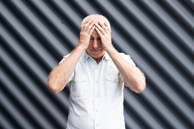 Foto uomo maggiore che tocca il suo fronte, emozioni espressive