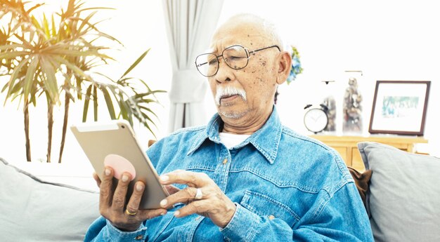 Photo senior man using digital tablet at home