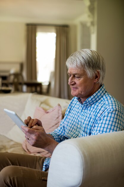 Senior man using digital tablet in living room