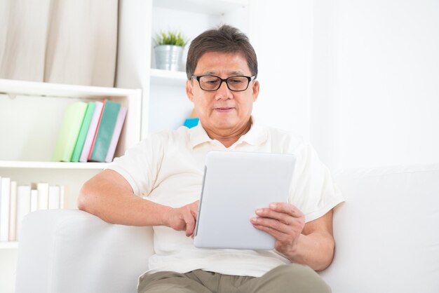 사진 집 의 소파 에 디지털 태블릿 을 사용하는 노인