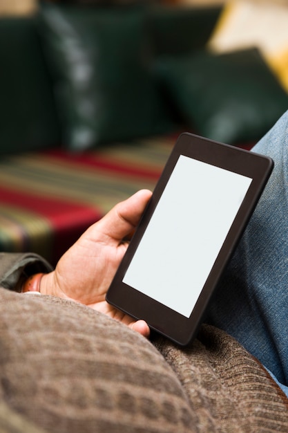 Senior man using an ebook reader in the sofa