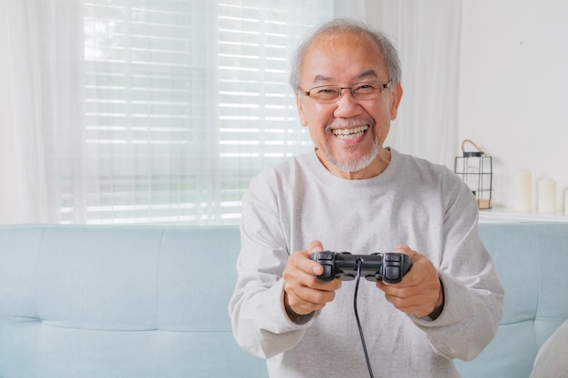 Старший мужчина использует джойстик старший держит джойстика, чтобы играть в игру