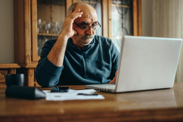 自宅でノートパソコンを使うシニア男性
