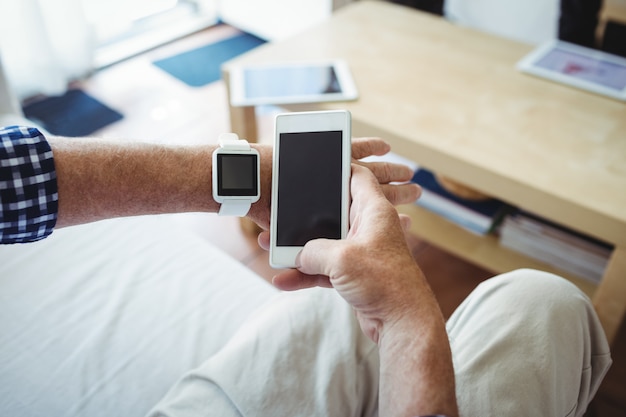 Senior man using mobile phone in living room