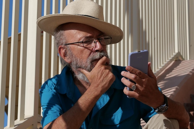 Photo senior man using mobile phone outdoor