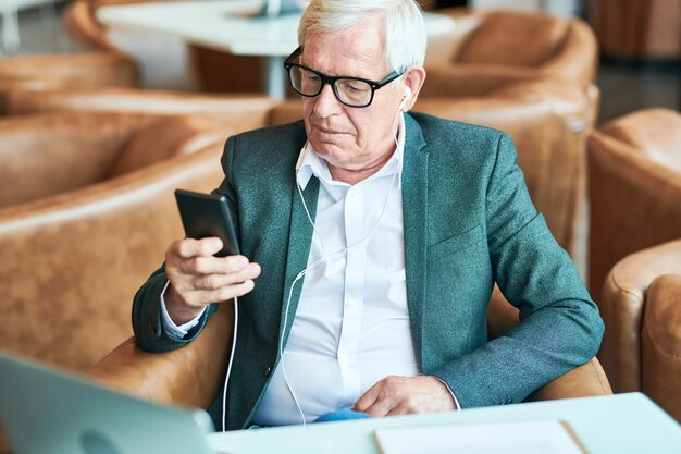 Senior man using smartphone in cafe