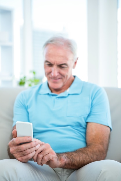 Старший мужчина, используя смартфон дома
