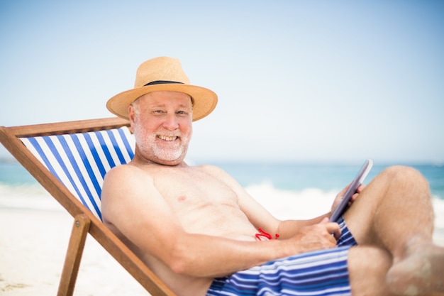 Старший мужчина с помощью планшета на пляже