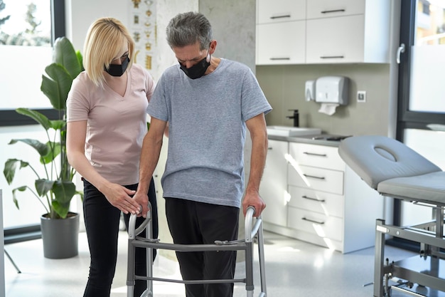 Foto uomo anziano che usa un passeggino con l'aiuto di un'infermiera