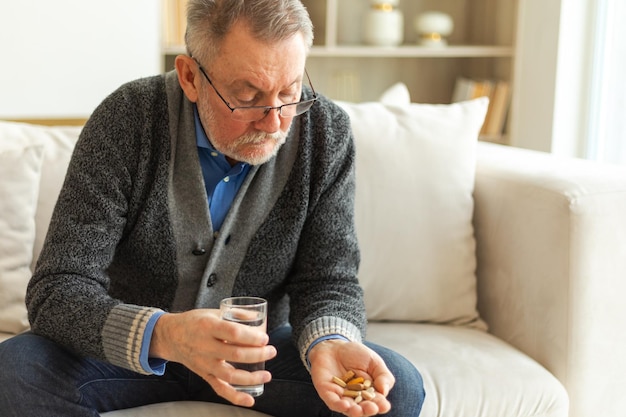 Senior man van middelbare leeftijd met medische pil en glas water volwassen oude senior grootvader nemen