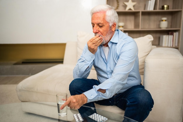 Senior man van middelbare leeftijd met medische pil en glas water volwassen oude senior grootvader nemen