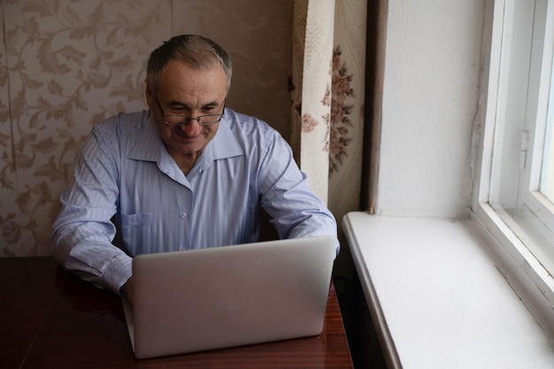 Senior man videoconferentie op laptop over houten bureau
