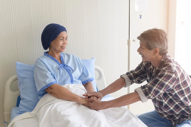A Senior man visiting cancer patient woman wearing head scarf at hospital