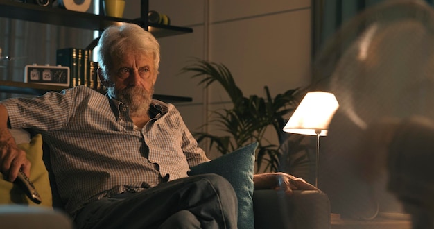 Photo senior man watching tv at home on a summer night fan in the foreground