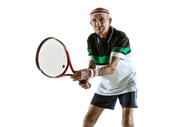 白い背景で隔離のテニスをしているスポーツウェアを着た年配の男性。体型の良い白人男性モデルは、アクティブでスポーティなままです。スポーツ、活動、動き、健康のコンセプト。コピースペース、広告。