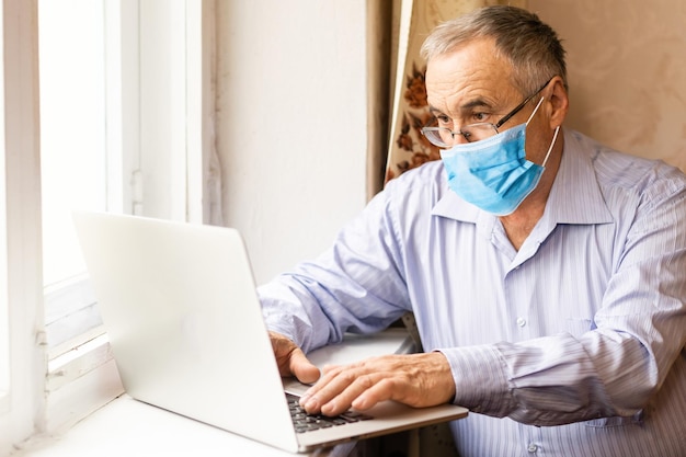 Senior man wearing surgical face mask at home.