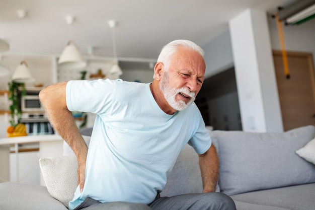 Photo senior man with back pain touches his back illustrating sciatica and sedentary lifestyle emphasizing spine health and the significance of healthcare and insurance in this stock image